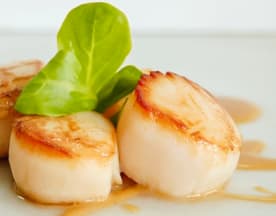Três vieiras perfeitamente seladas, com uma crosta dourada, tenras e suculentas, guarnecidas com alface fresca e regadas com um molho saboroso.
