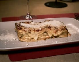 Lasaña con capas de pasta, salsa bechamel cremosa y relleno de carne, cubierta con queso gratinado.