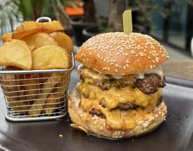 Burger copieux avec deux galettes de boeuf juteuses, fromage cheddar fondu et sauce crémeuse, accompagné de quartiers de pommes de terre dorées et croustillantes.