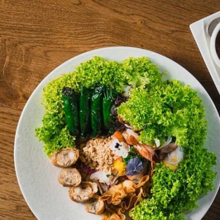 Bunte Salatvariation mit frischen Blattsalaten, gegrillten Garnelen, zarten Hähnchenstücken und knusprigen Wontonstreifen, serviert mit drei verschiedenen Dipsaucen.