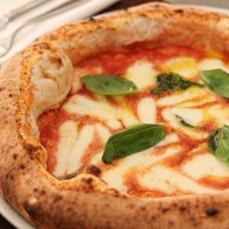 Pizza napolitaine classique avec une croûte épaisse et moelleuse, garnie de sauce tomate riche, de mozzarella fondue et de feuilles de basilic frais.