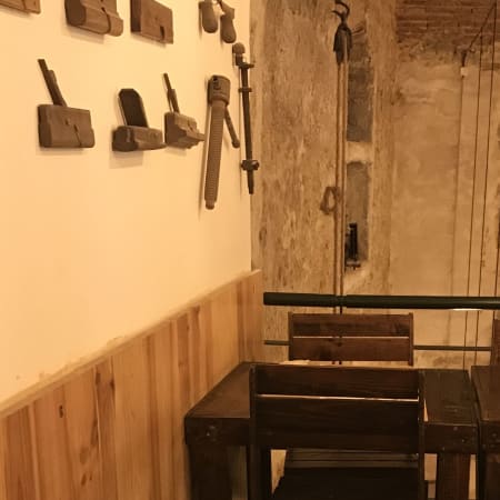 Interior rústico de restaurante com paredes de tijolo exposto e detalhes em madeira, mesas simples e cadeiras a condizer, criando uma atmosfera acolhedora.
