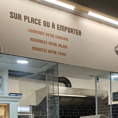 Extérieur du restaurant "TEBSI" avec une enseigne indiquant des options de repas sur place ou à emporter, mettant en avant des plats personnalisables dans un design moderne et accueillant.