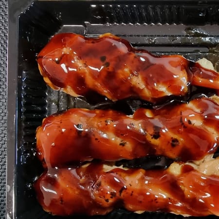 Tres brochetas de pollo a la parrilla glaseadas con salsa teriyaki, acompañadas de arroz pegajoso y semillas de sésamo.