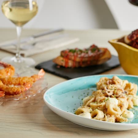 Pasta orecchiette en salsa cremosa, decorada con hierbas picadas y migas de pan.
