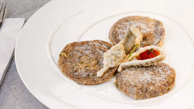 Ravioli* di pasta fresca agli spinaci* con lacrime di nero di seppia* farciti con gamberi*, ricotta vaccina, zenzero su datterini e gel di zafferano (1,2,3,8,9,12) - La Rotonda di Lomazzo Ristorante e Pizzeria