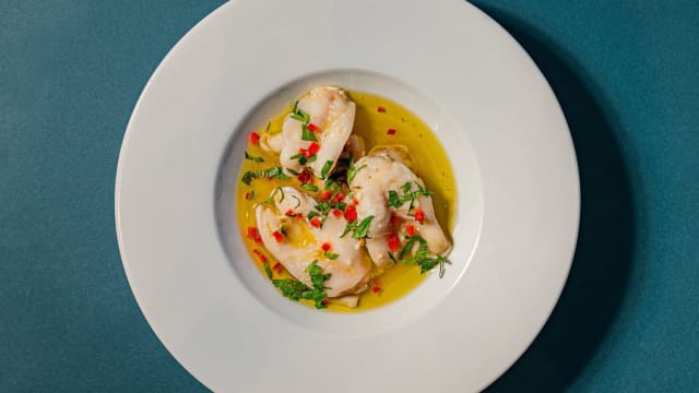 Camarões escalfados dispostos em um caldo leve e aromático, infundido com notas de citrinos e ervas, guarnecidos com coentro picado e pedaços de pimenta vermelha.