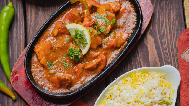 Murghi tikka masala (spécialité du Chef ) : suprême de dés de poulet marinés longuement dans une sauce aux épices légèrement citronnée, puis présenté sur plaque chauffante, le tout saupoudré de coriandre - Aux Indes, Lille