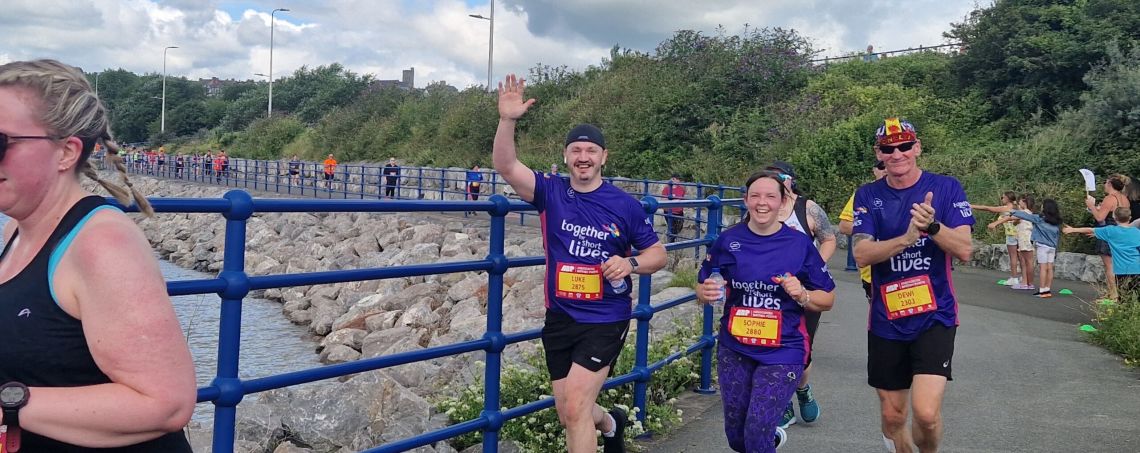 three runners smiling at camera as they race for Together for Short Lives