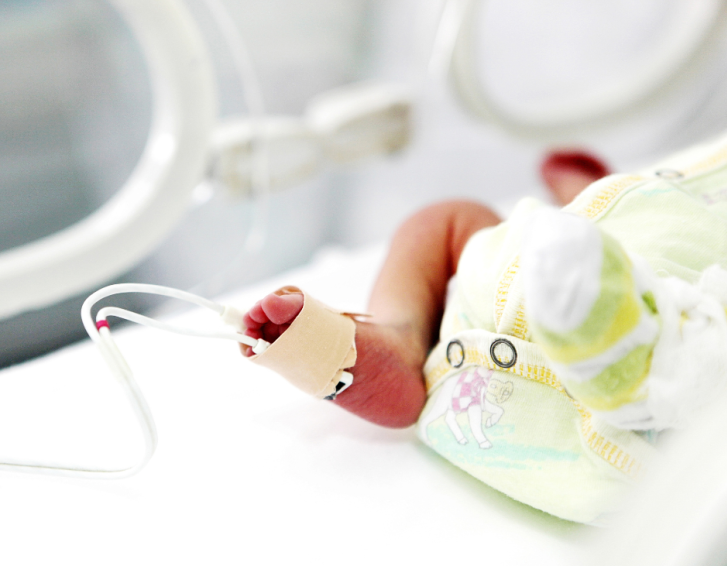 A premature baby's foot, with monitor attached, in an incubator