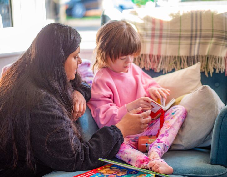 a young girl reading a book with a carer