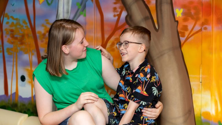 Mum talking to her son, sat in front of a colourful painted wall