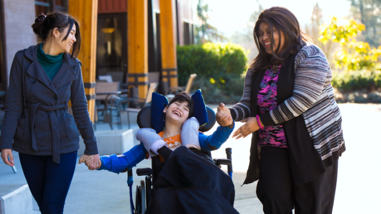 Child in wheelchair with two carers