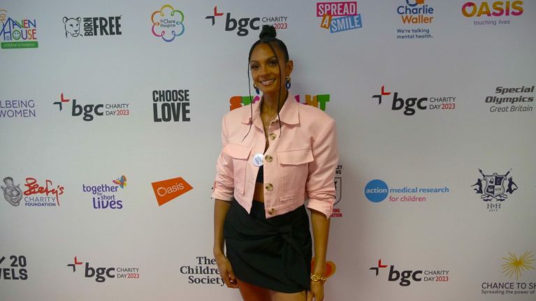 Woman in pink jacket smiling standing on red carpet