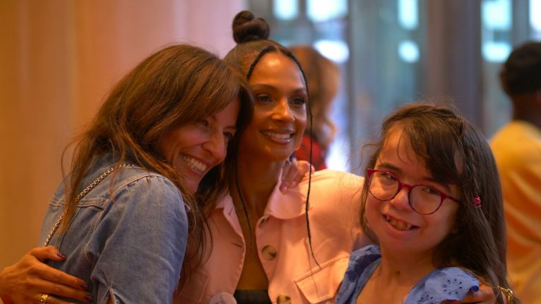 Two women smiling hugging a girl