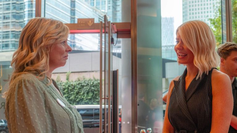 Two women talk to each other in the lobby of an office building