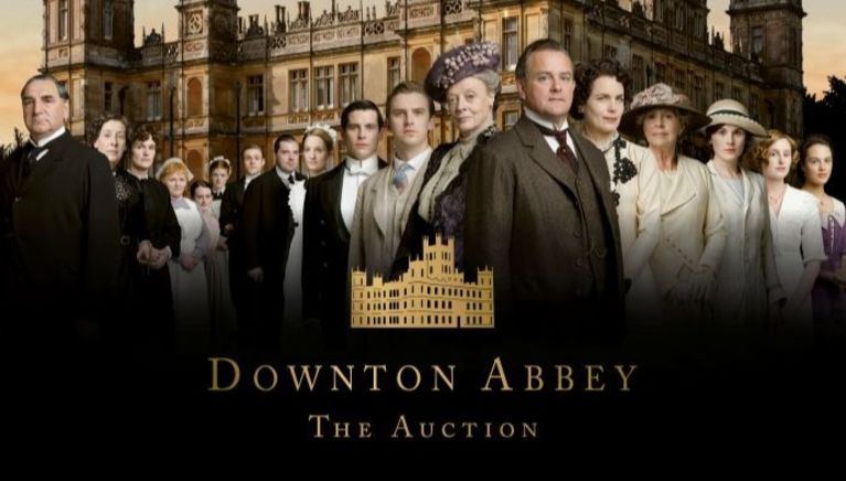 The cast of Downtown Abbey assembled in front of a stately home.
