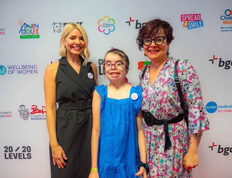 Two women and a young girl smile at the camera on a red carpet