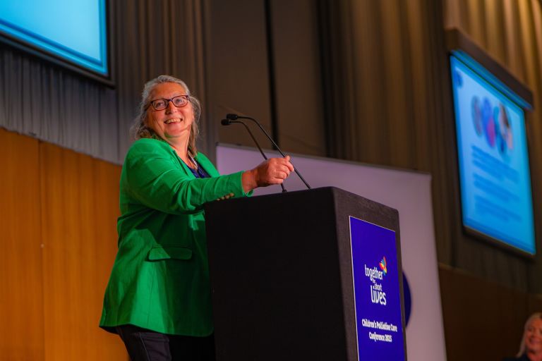 A woman standing at a podium at a Together for Short Lives conference