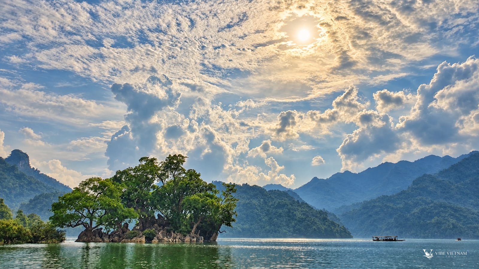 Hồ Ba Bể phẳng lặng với đảo cây xanh và núi đá vôi bao quanh dưới nắng sớm