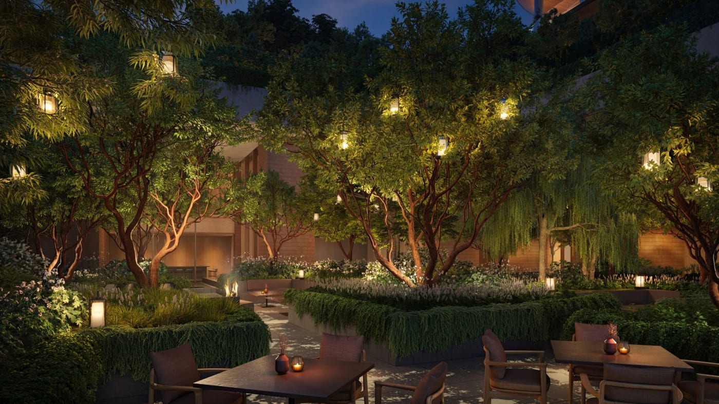 Rendu du jardin et de la terrasse de l'hôtel Aman Beverly Hills le soir, sous les arbres éclairés de lanternes