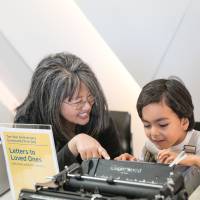 Photo of C.K. Itamura working on a craft project with a child