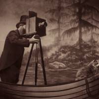Sepia-toned photograph of a man standing in a boat and taking a photograph