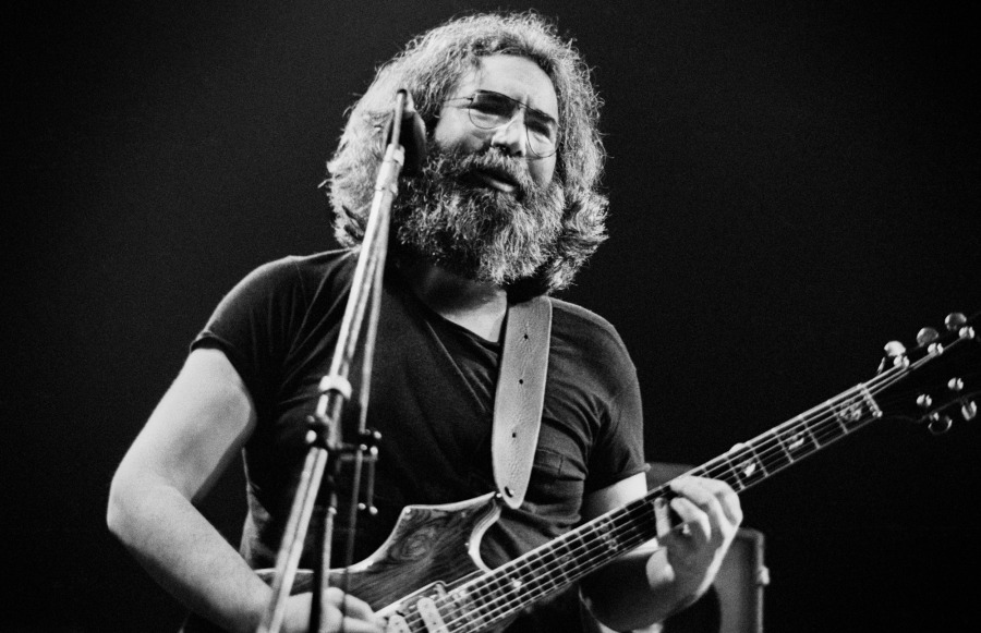 A black and white photograph of Jerry Garcia playing guitar.