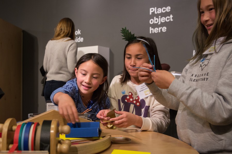 Two girls work on a craft project together.