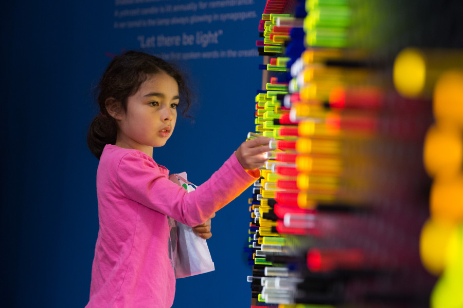 Young girl gazing at a wall of colorful LED light pins