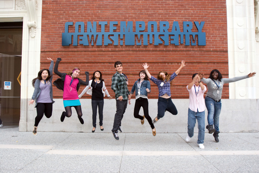 A group of teenagers jumping into the air in front of The CJM