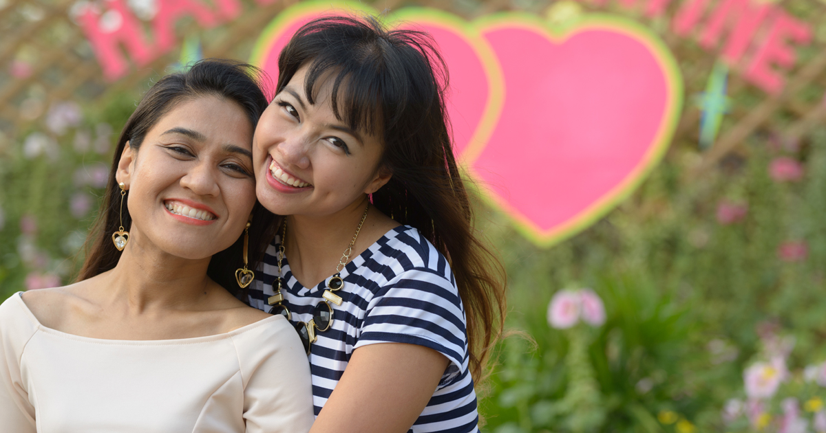 A couple smiling in front of two hearts A couple smiling in front of two hearts
