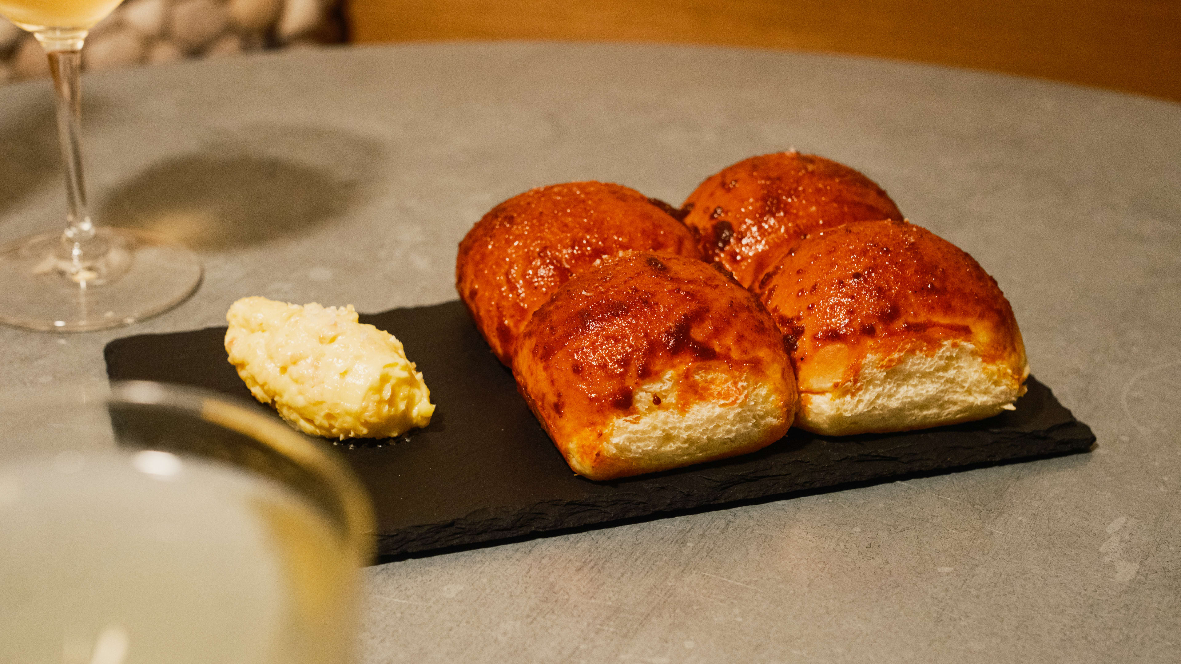 plate of four dinner rolls with small pat of butter on a slate plate