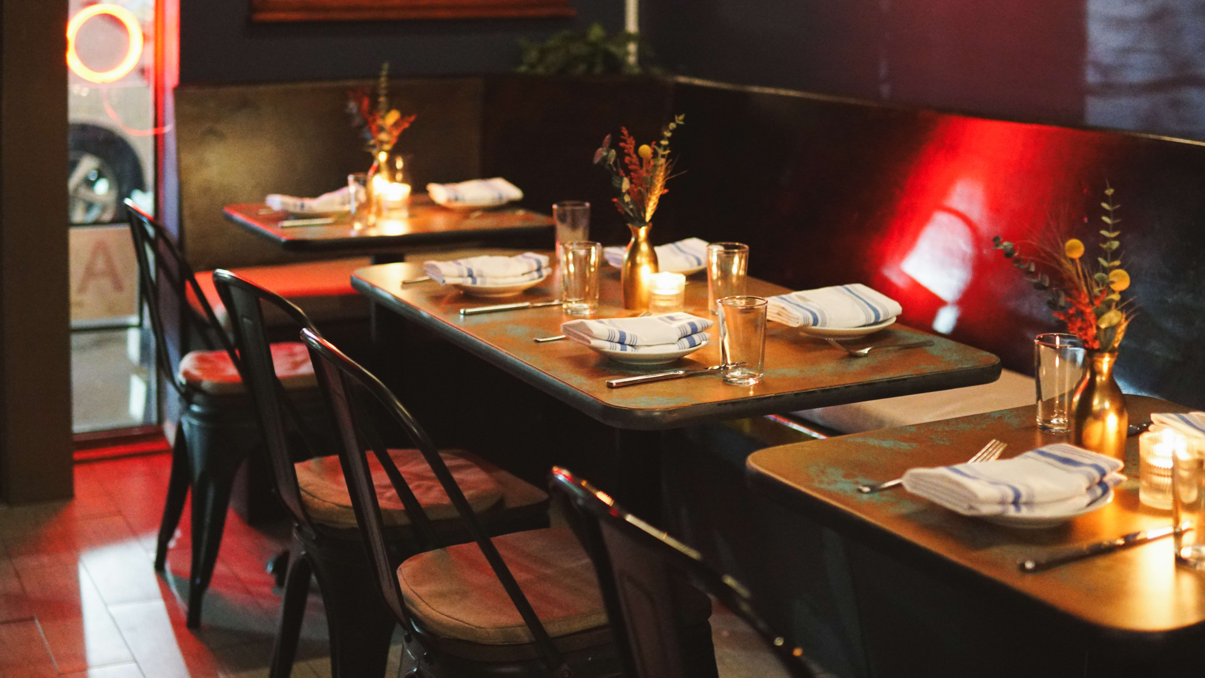 Small tables at Ramro with a red glow of their neon signage.