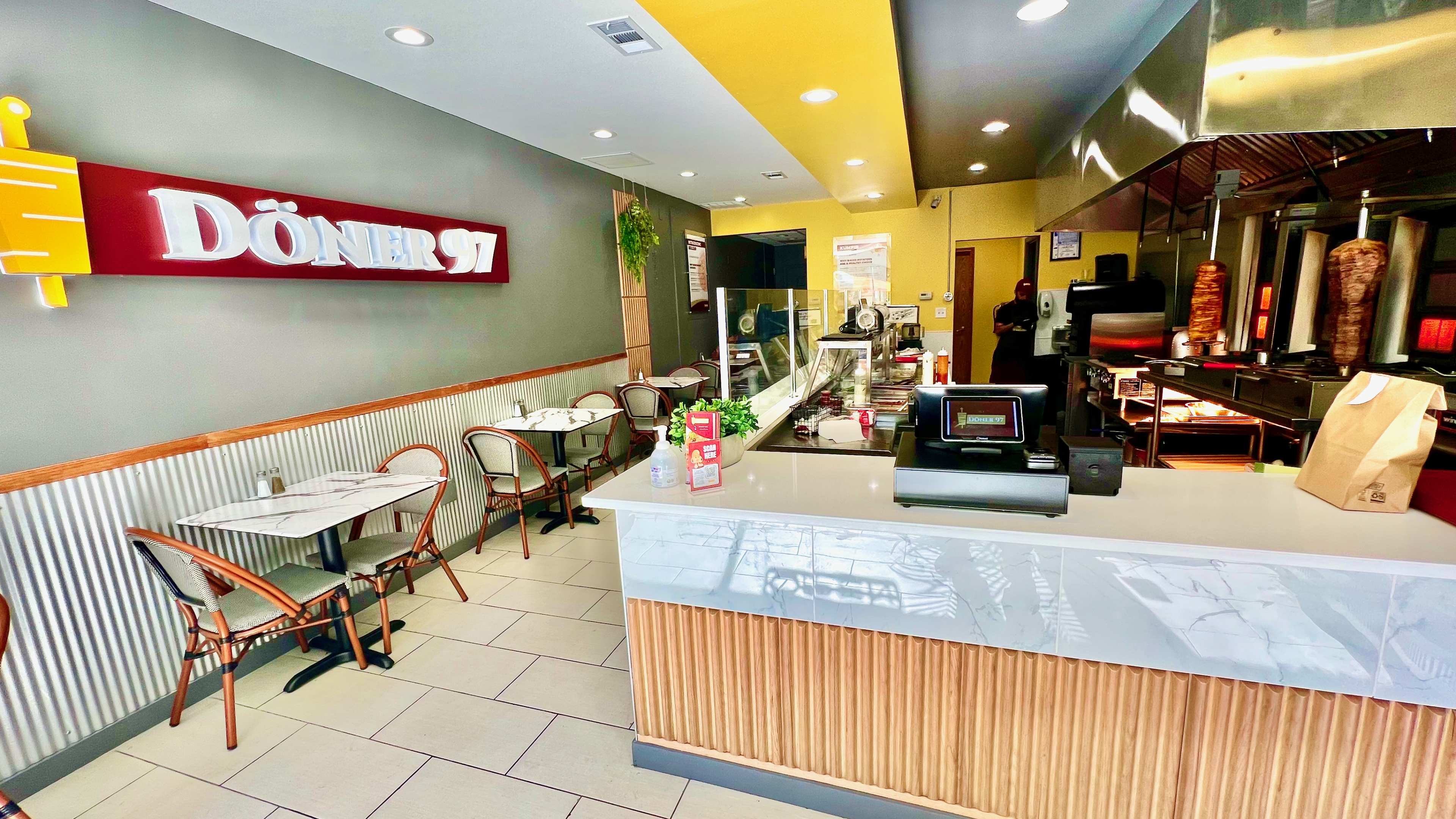 The interior of Döner 97 in Chicago with a view of the counter and three tables.