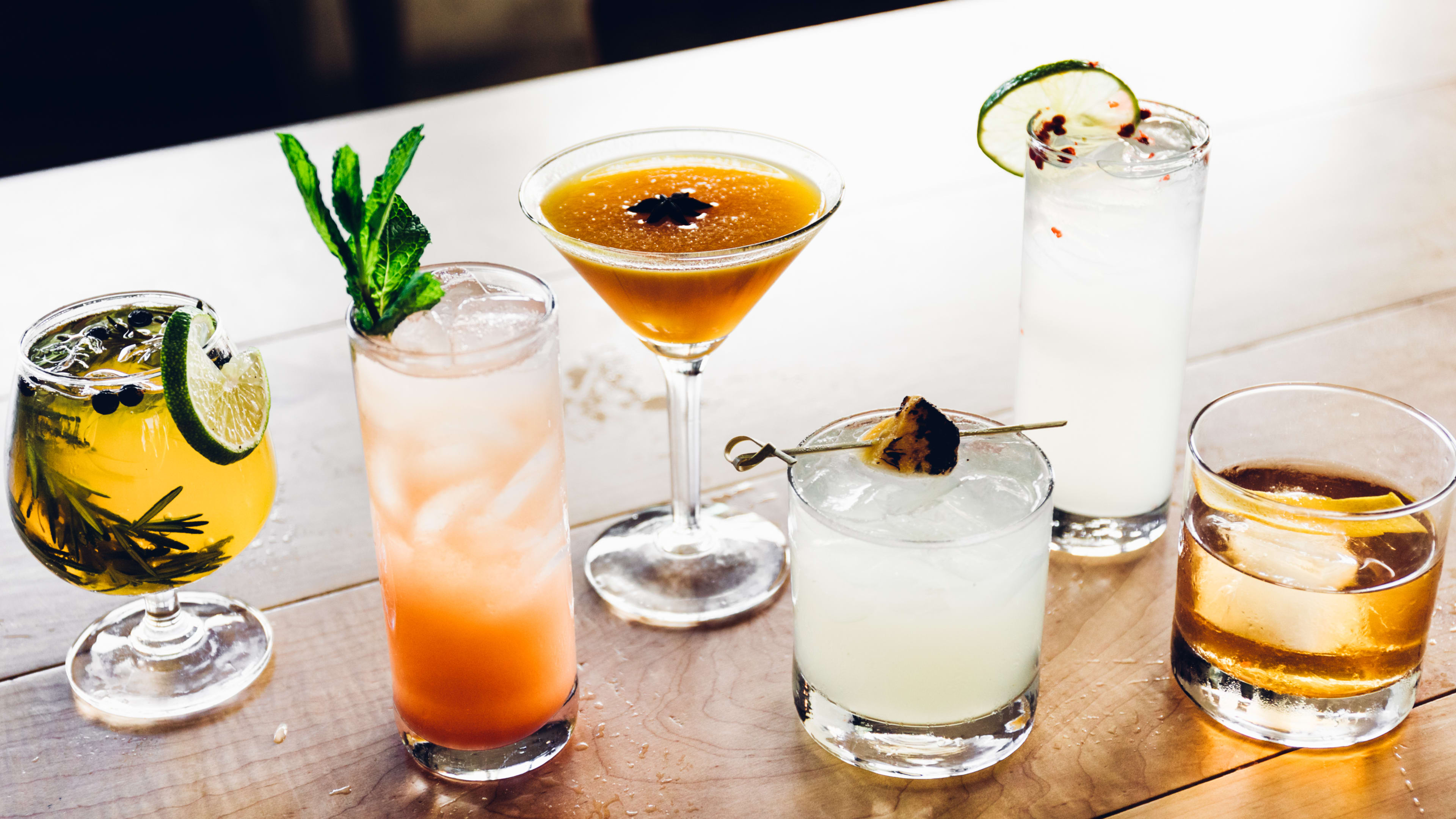 A spread of cocktails in different sized glasses with different garnishes