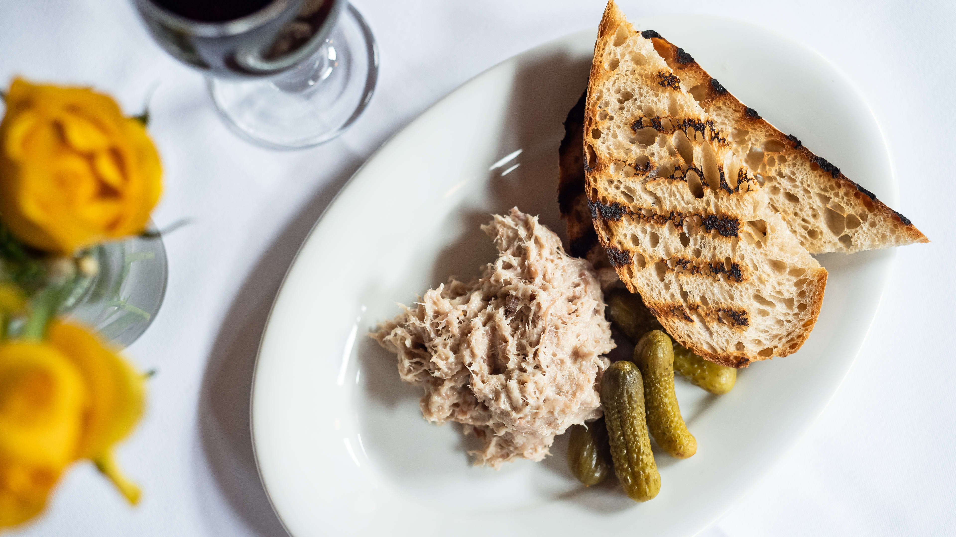 A plate of rilletes with cornichons and toasted bread and a glass of red wine at The French House.