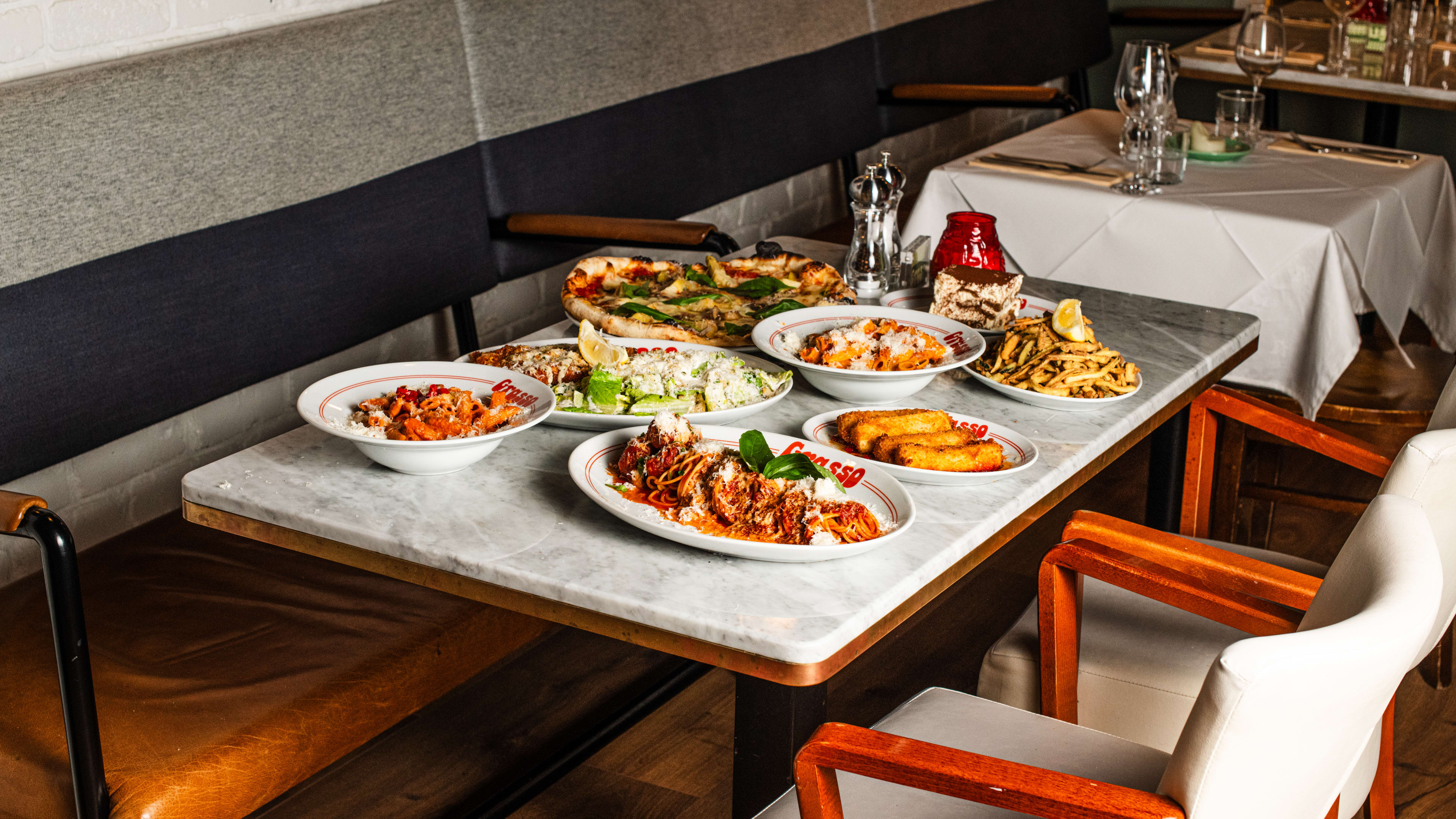 Italian dishes like pasta and pizza on a marble-look table.