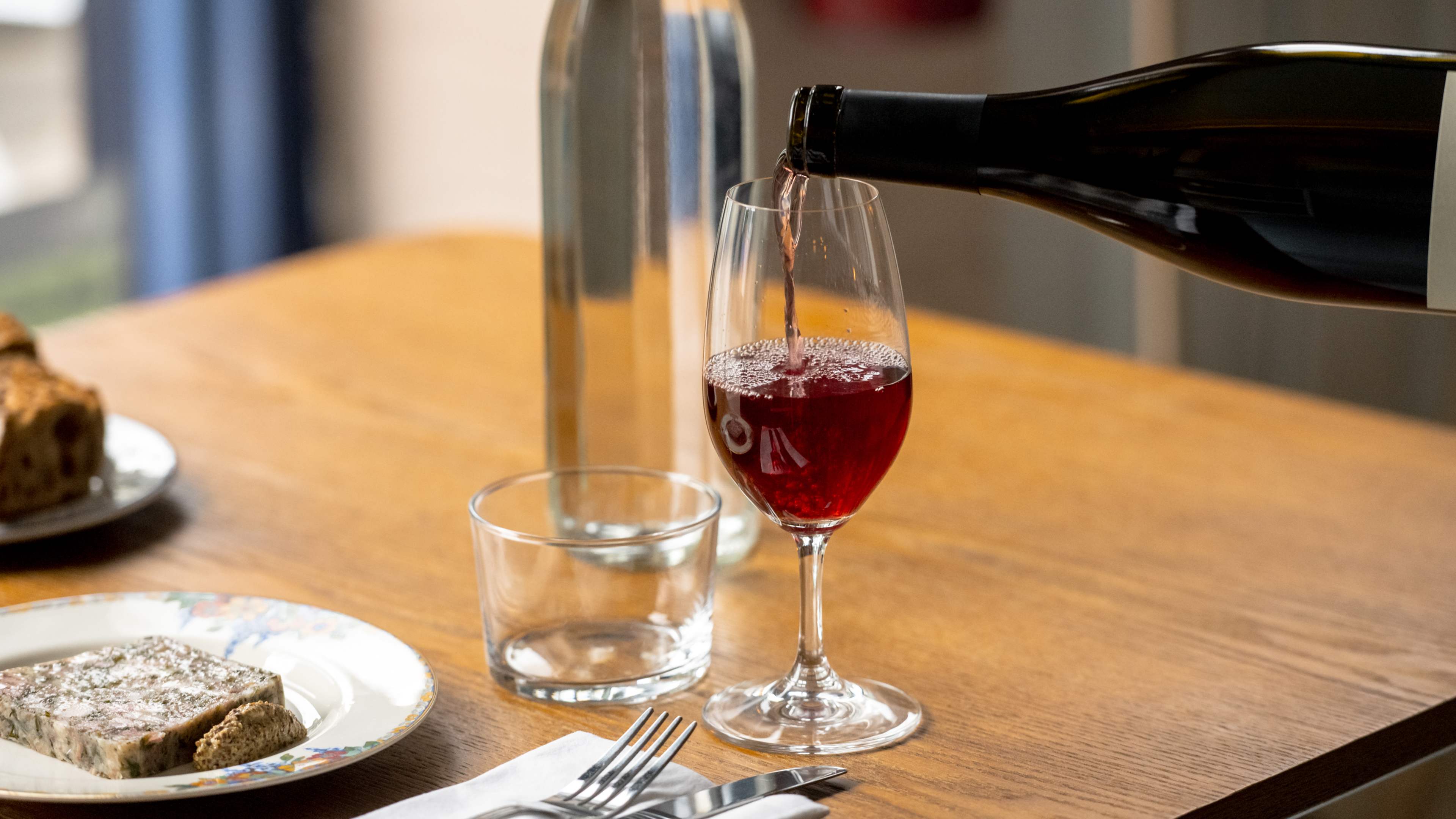 A bottle pouring red wine into a glass.