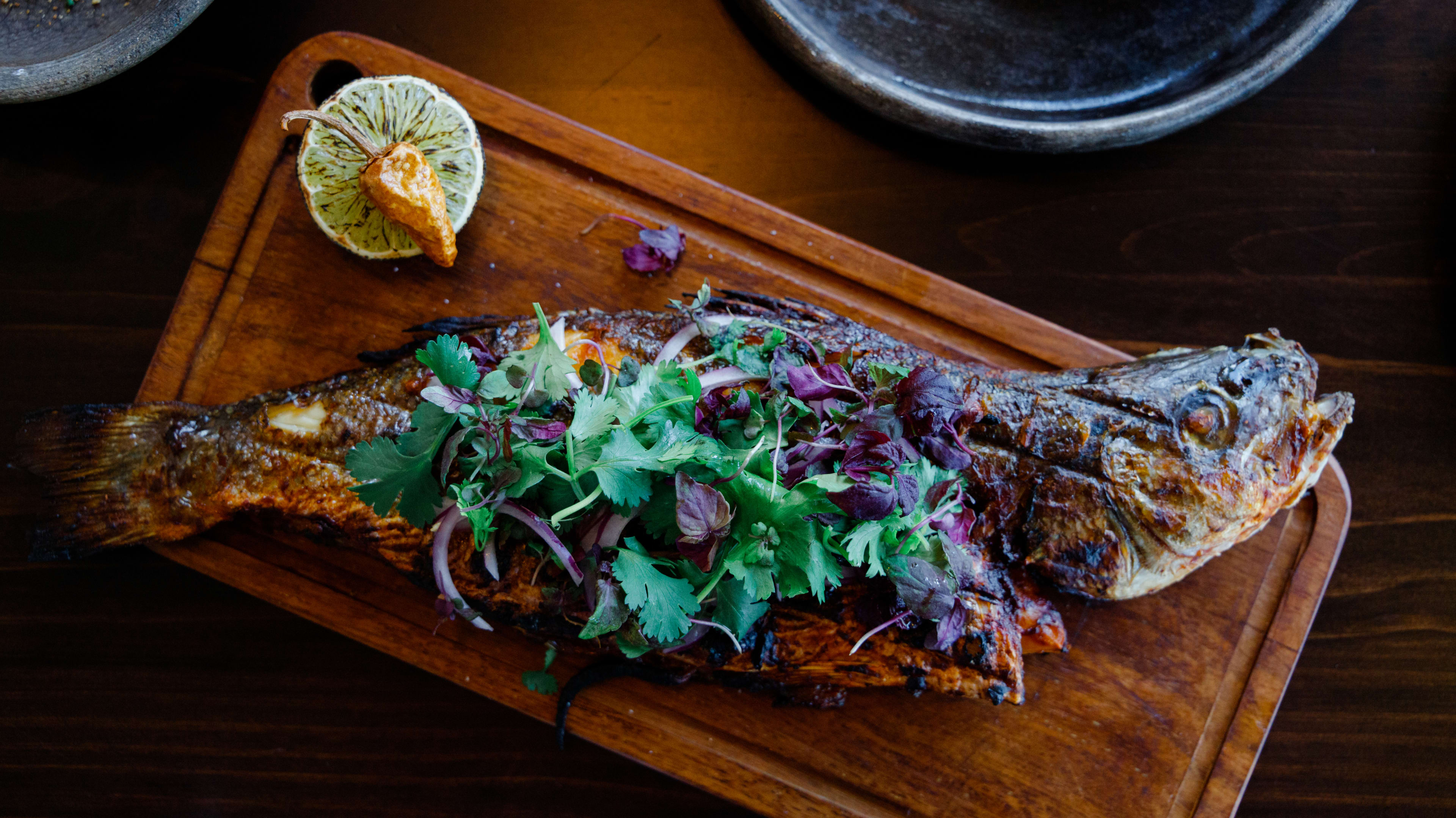 A whole fish served on a wooden board from Jūn.