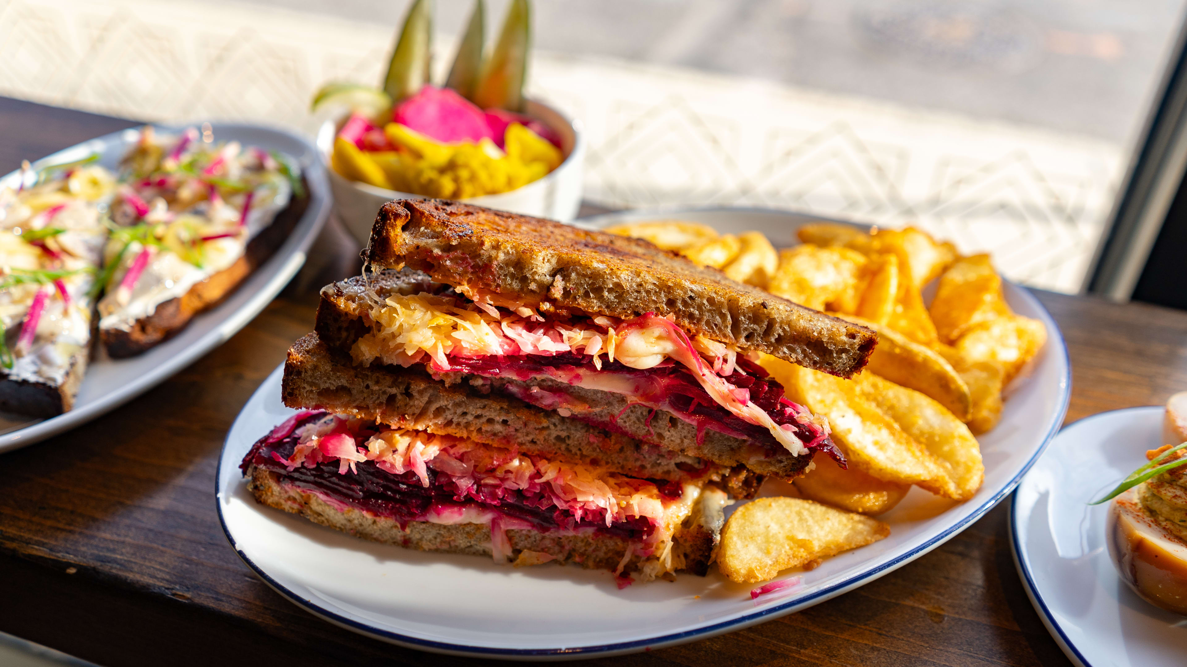 Beet pastrami sandwich on rye bread with side of potato chips at Lehrhaus
