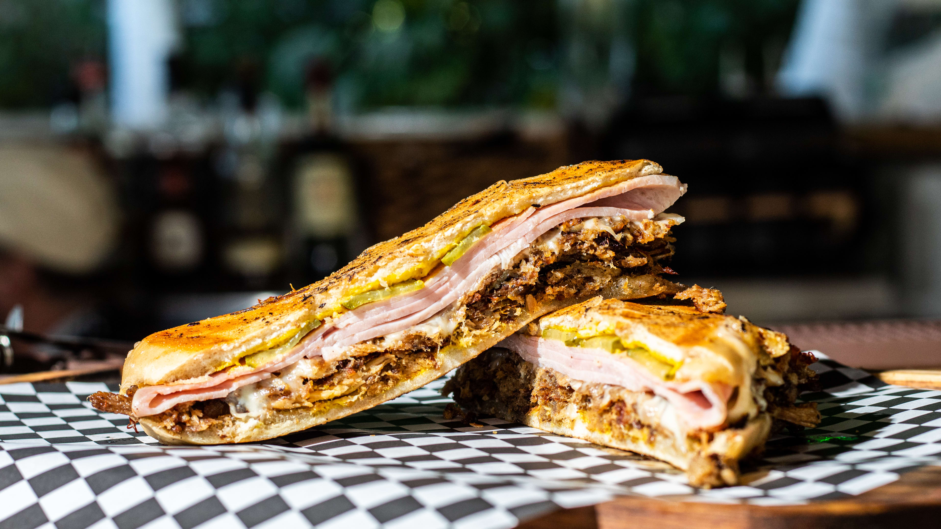 Pressed sandwich with meat and cheese on checkered paper