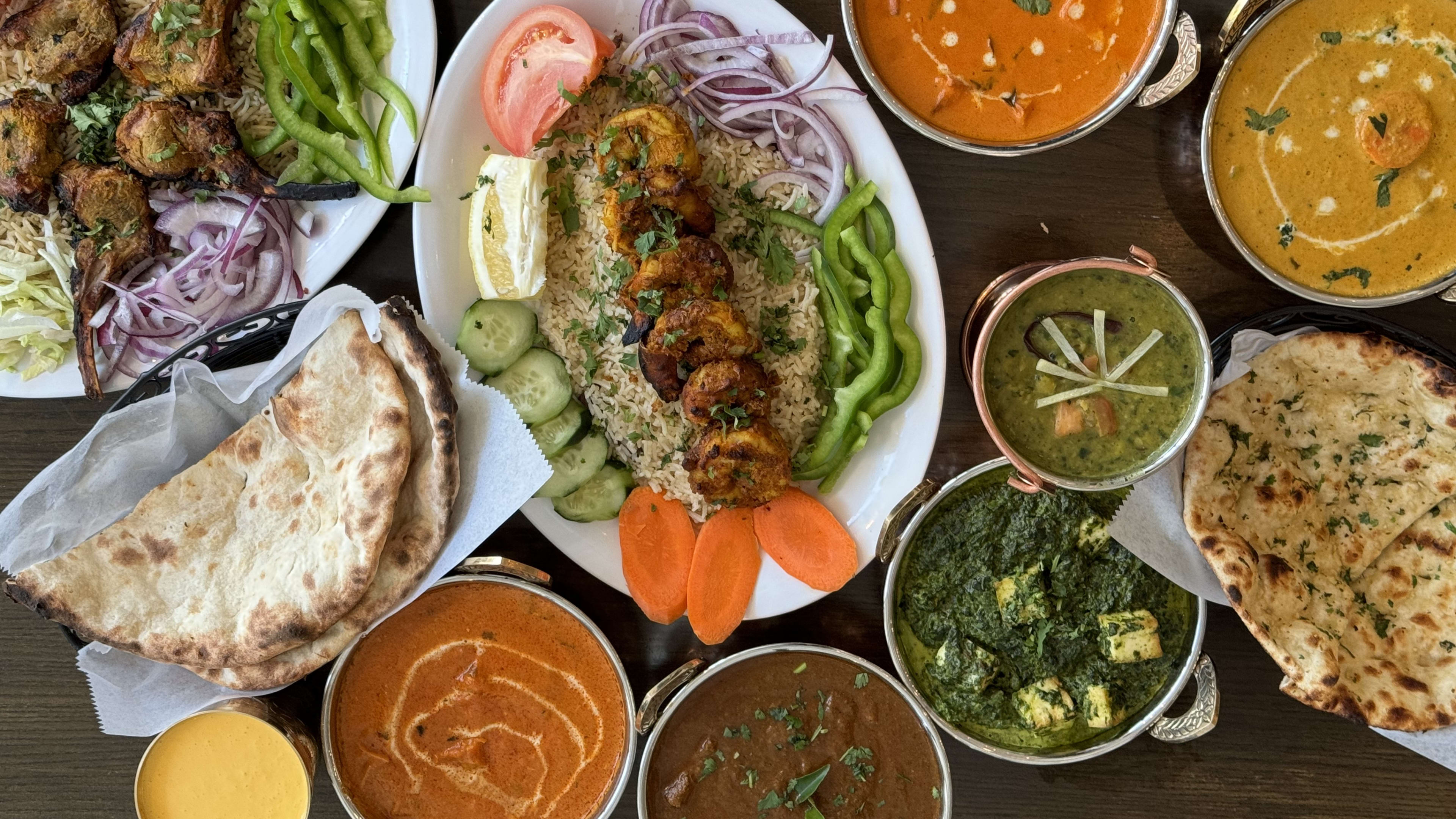 Large spread of curries, naan, and a platter of meats and rice