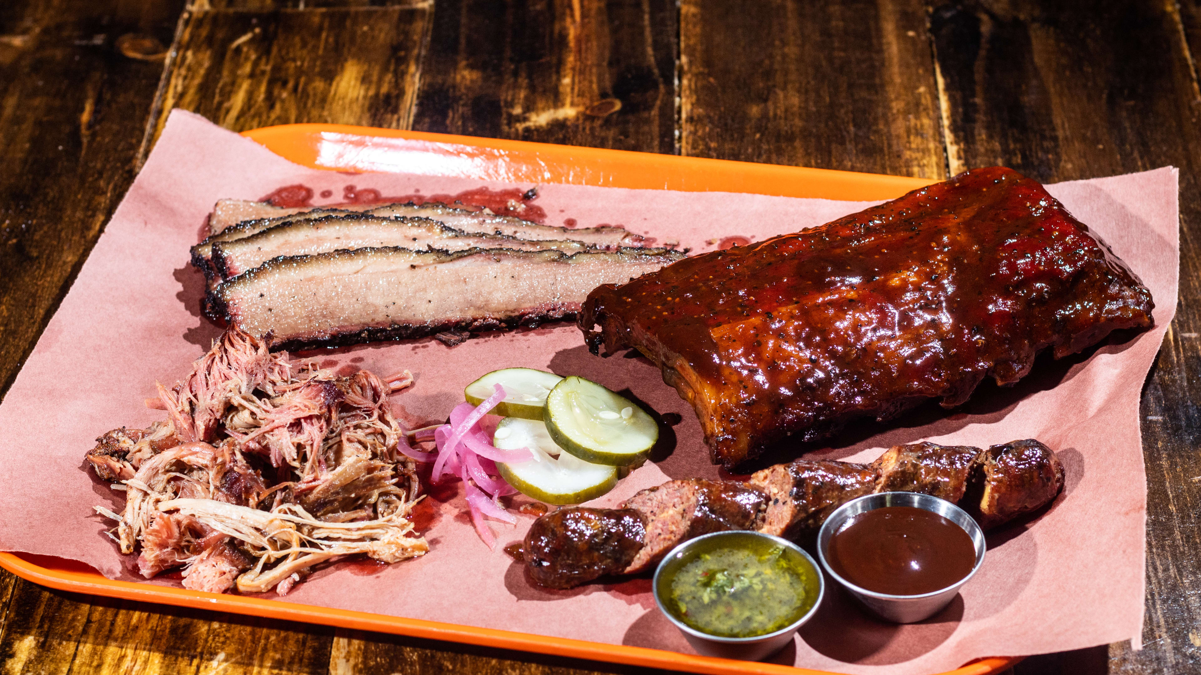 tray of ribs, brisket, pulled pork, pickles, and sauces