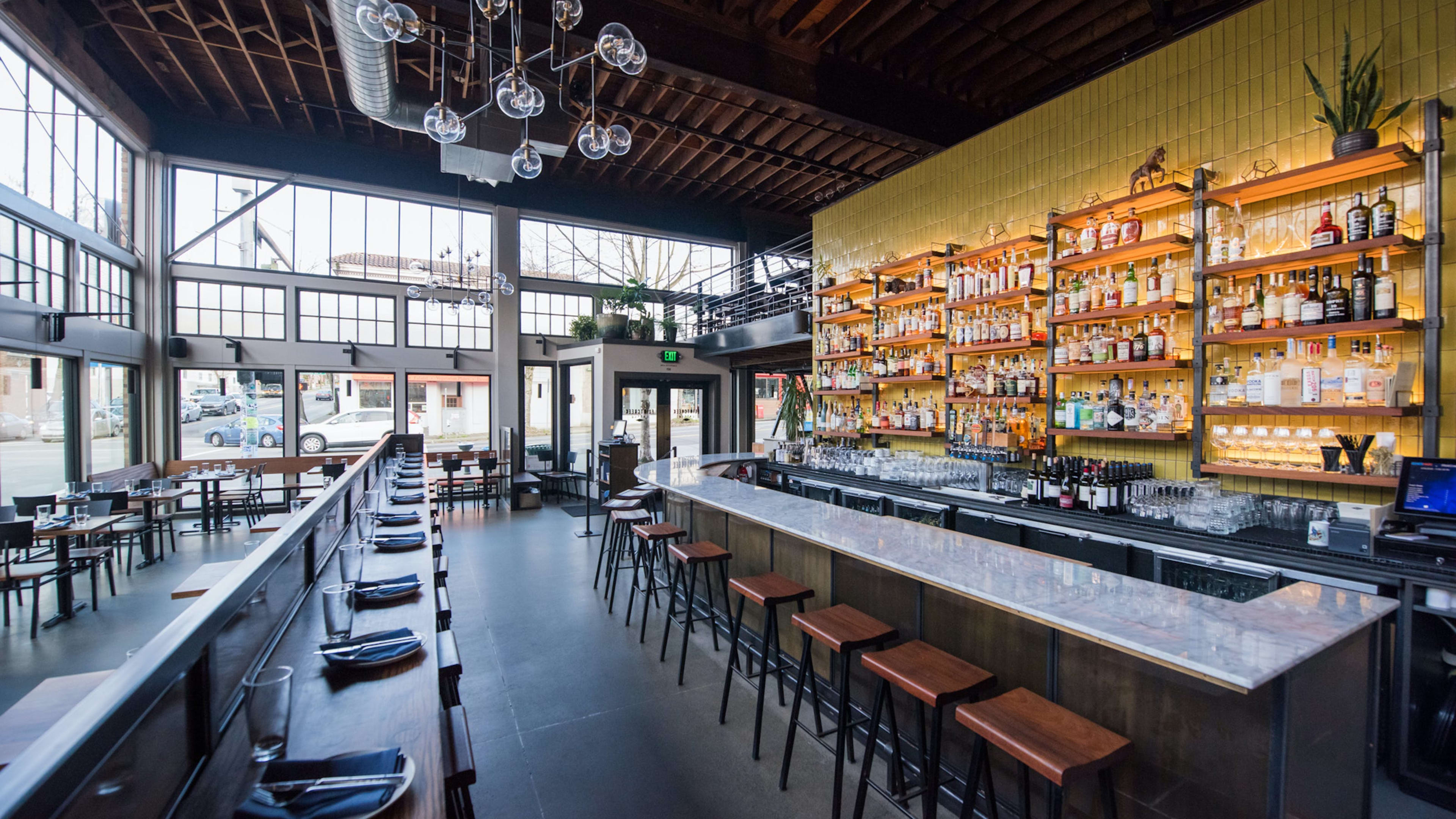 Steakhouse interior with a marble bar, yellow tiled walls, and modern lighting fixtures.