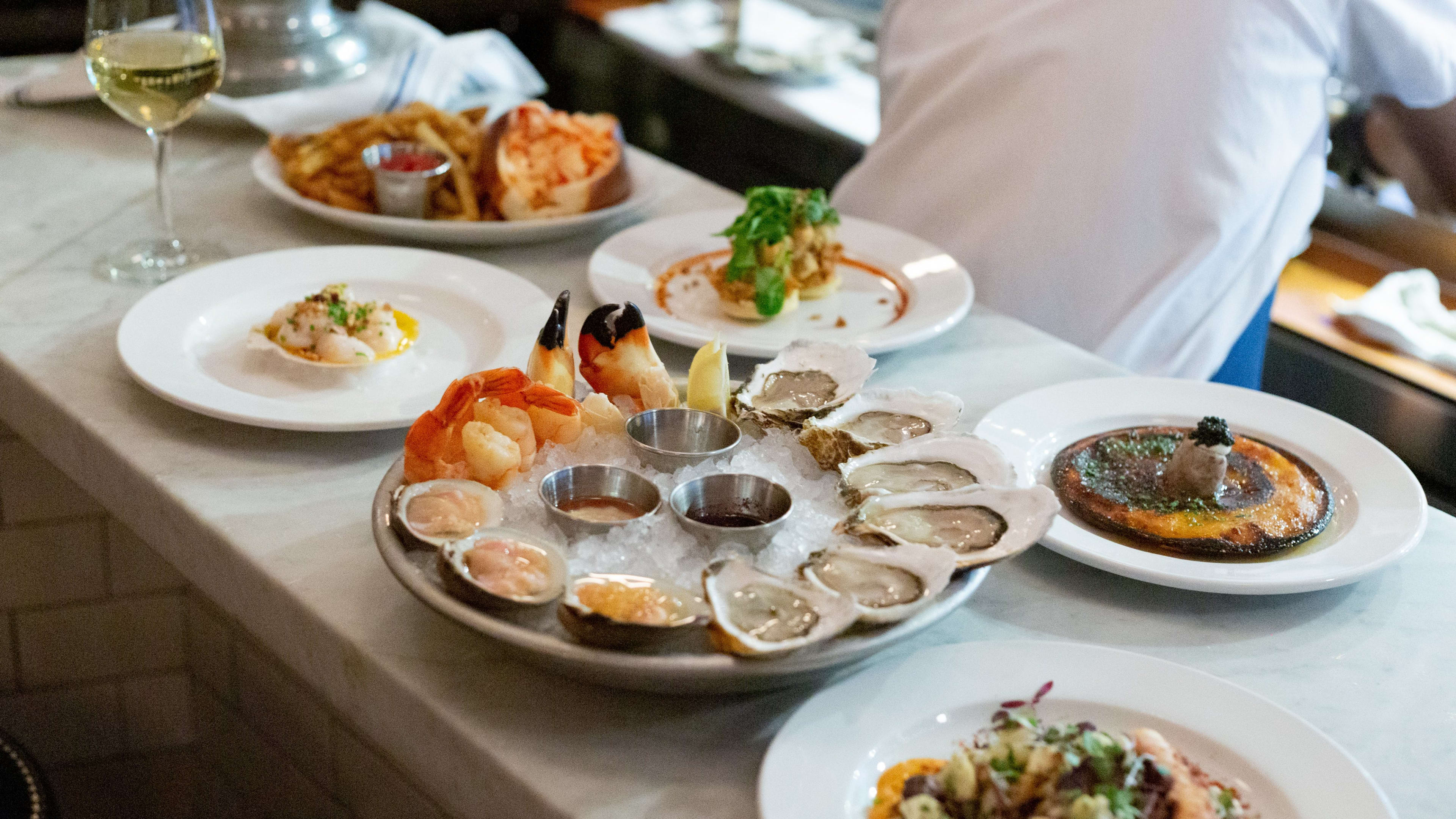 Plates of oysters, crab claws, and other seafood on the bar at Neptune Oyster.