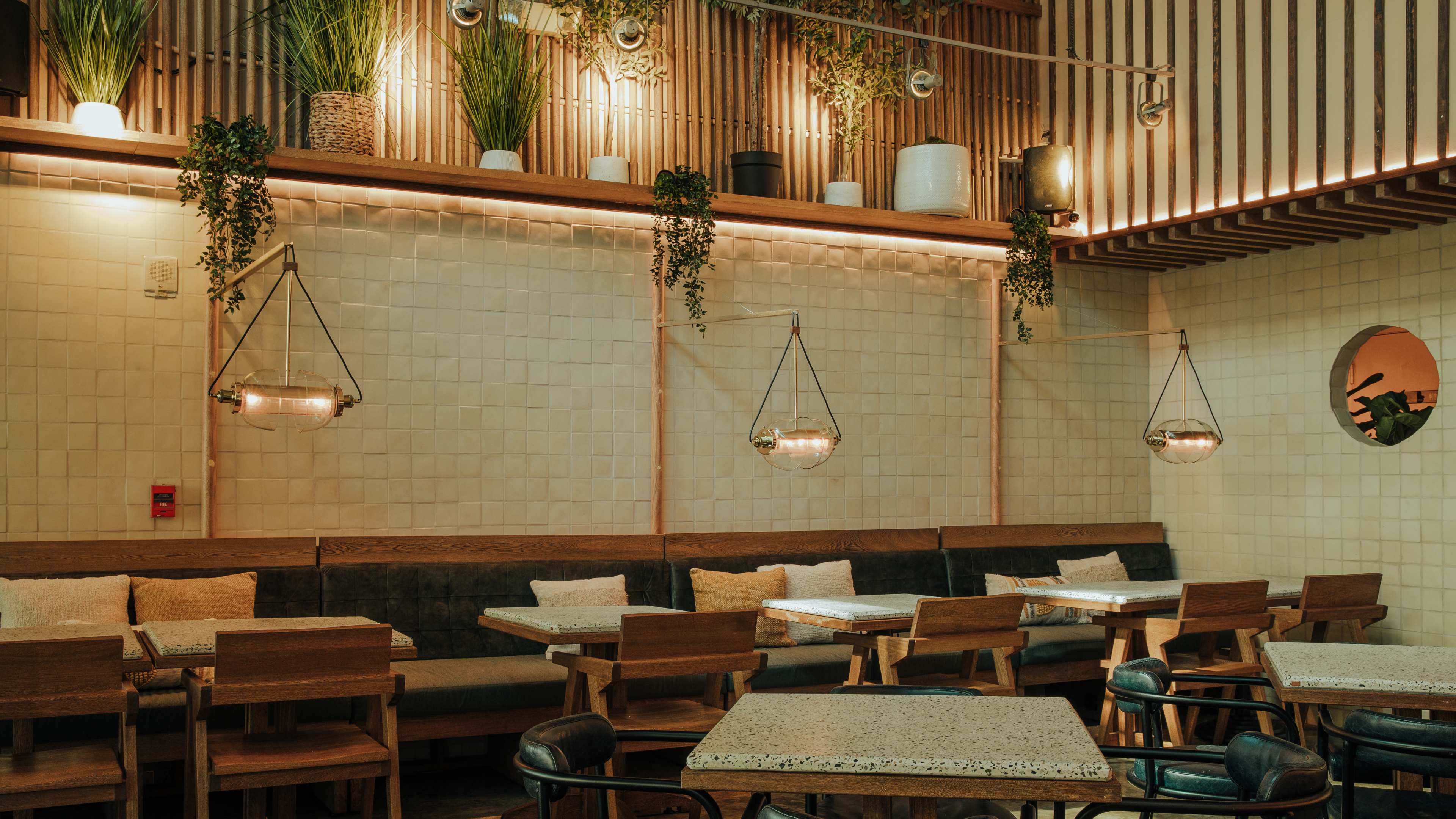 brick walled restaurant interior with low lighting and lots of plants