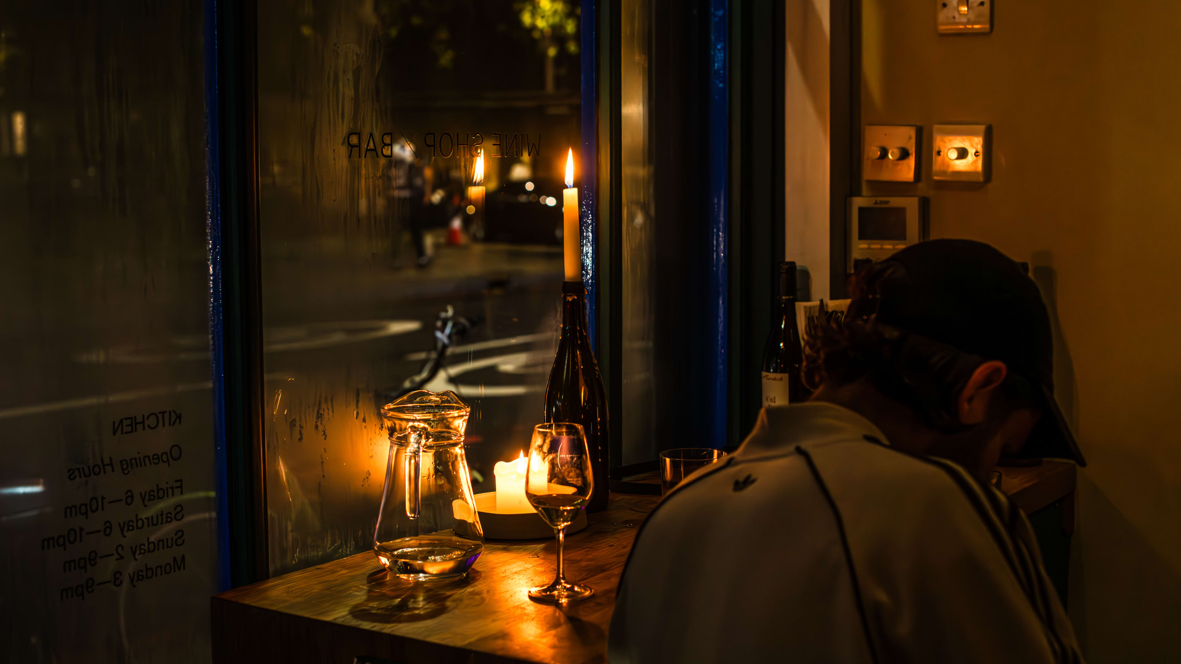 A person sitting at the candle-lit window seat with a glass of wine