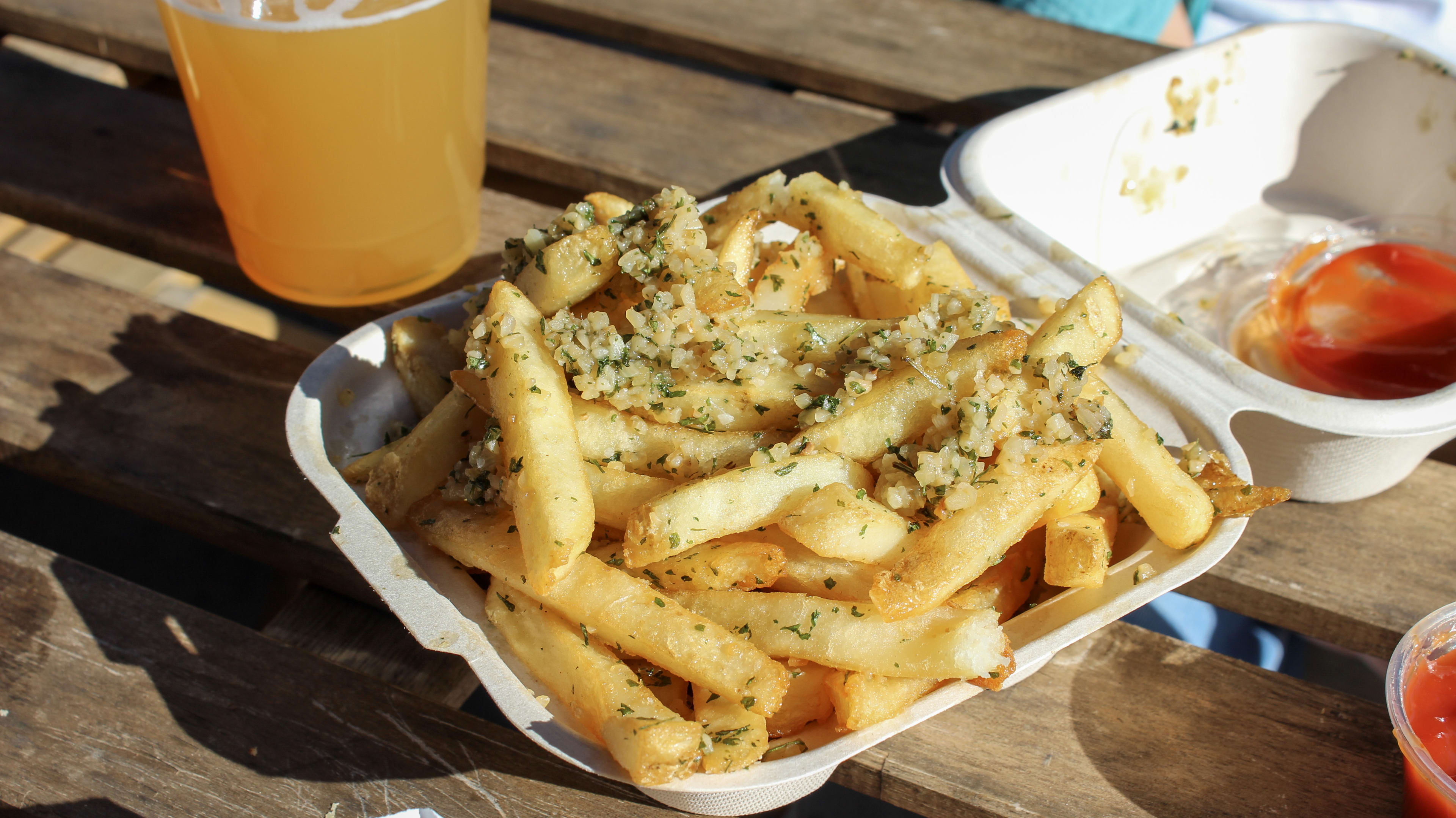 A takeout container full of seasoned fries.