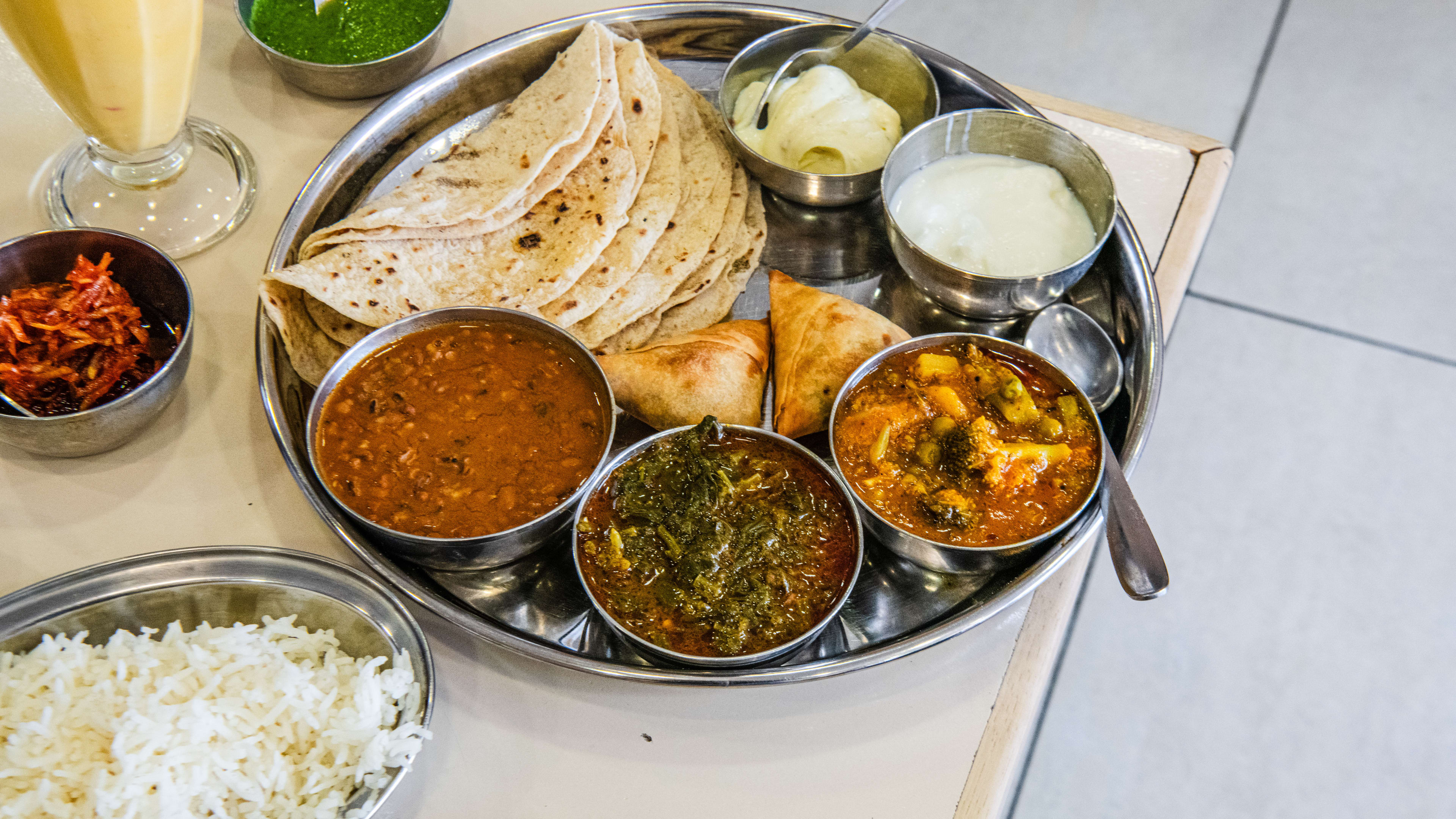 A vegetarian thali plate at Asher's Africana with a mango lassi on the side.